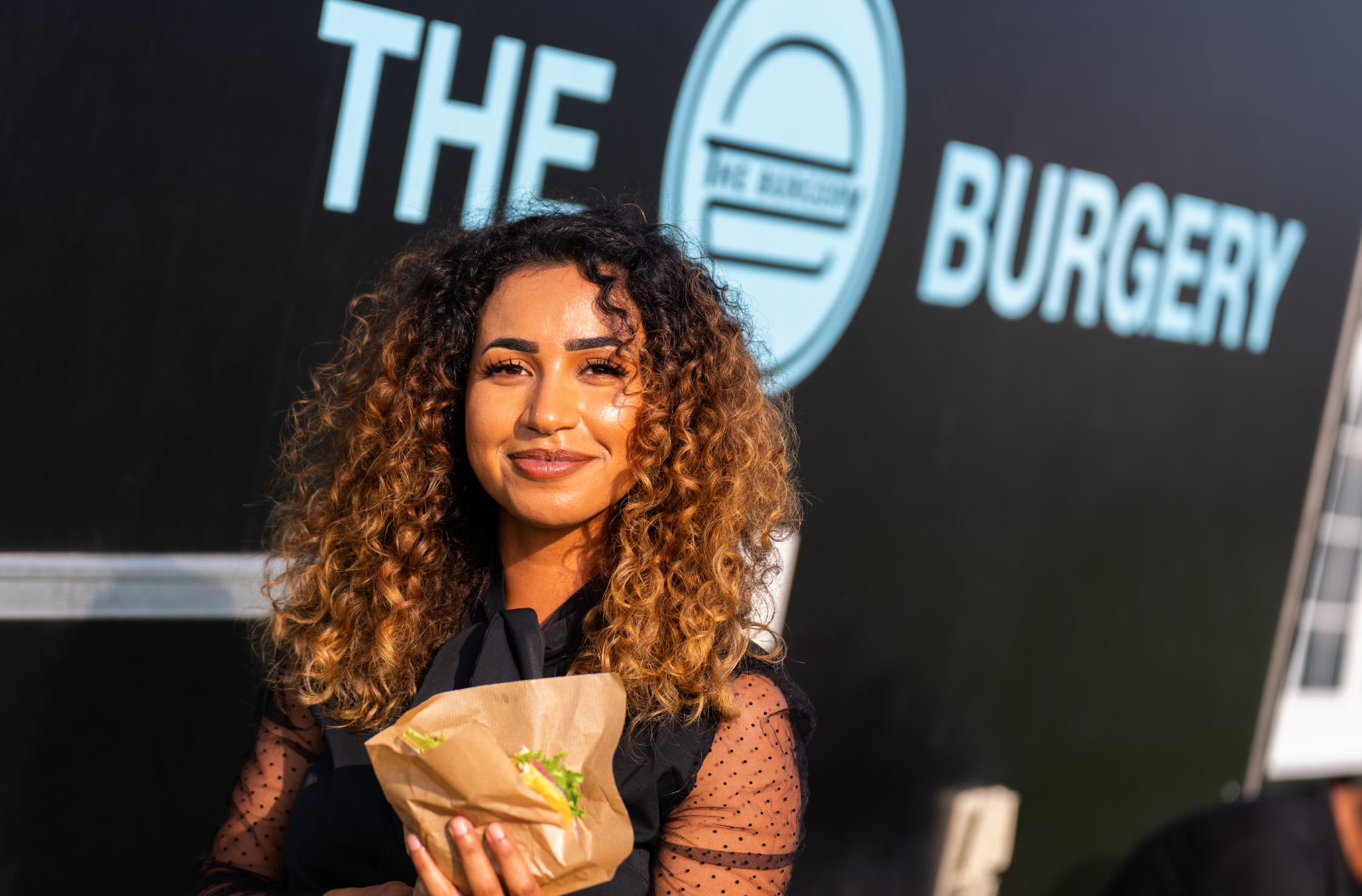 Smilende medarbejder med burger fra The Burgery